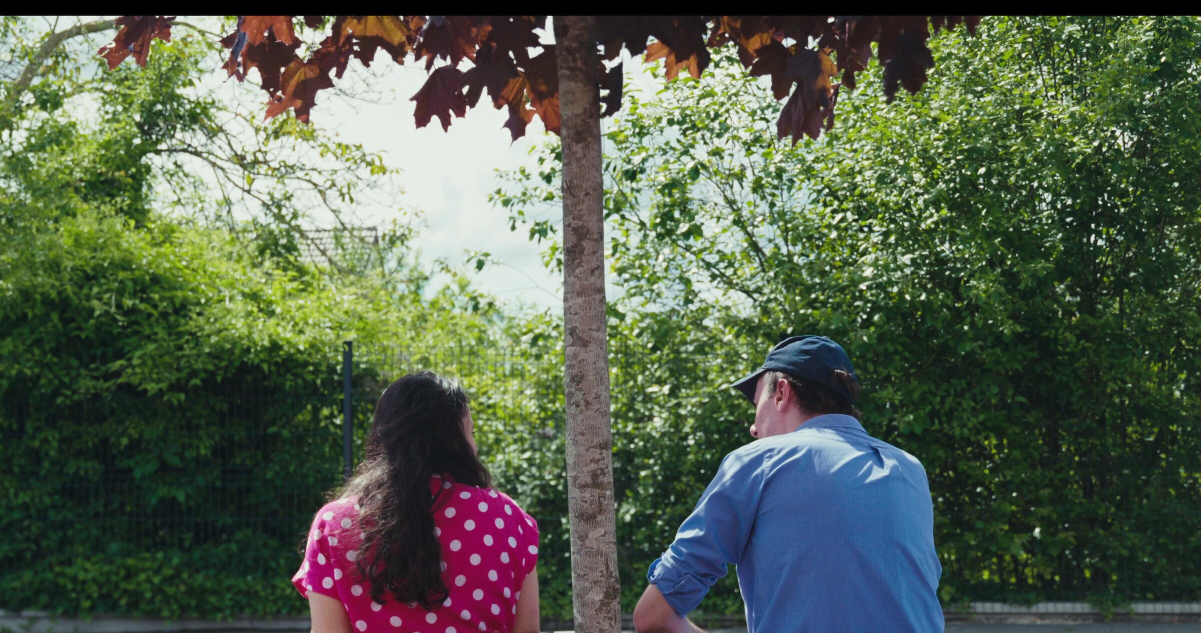 Couple de dos devant un arbre rouge, plan poitrine. Inès Berdugo et Antoine Morin, Création en Cours.